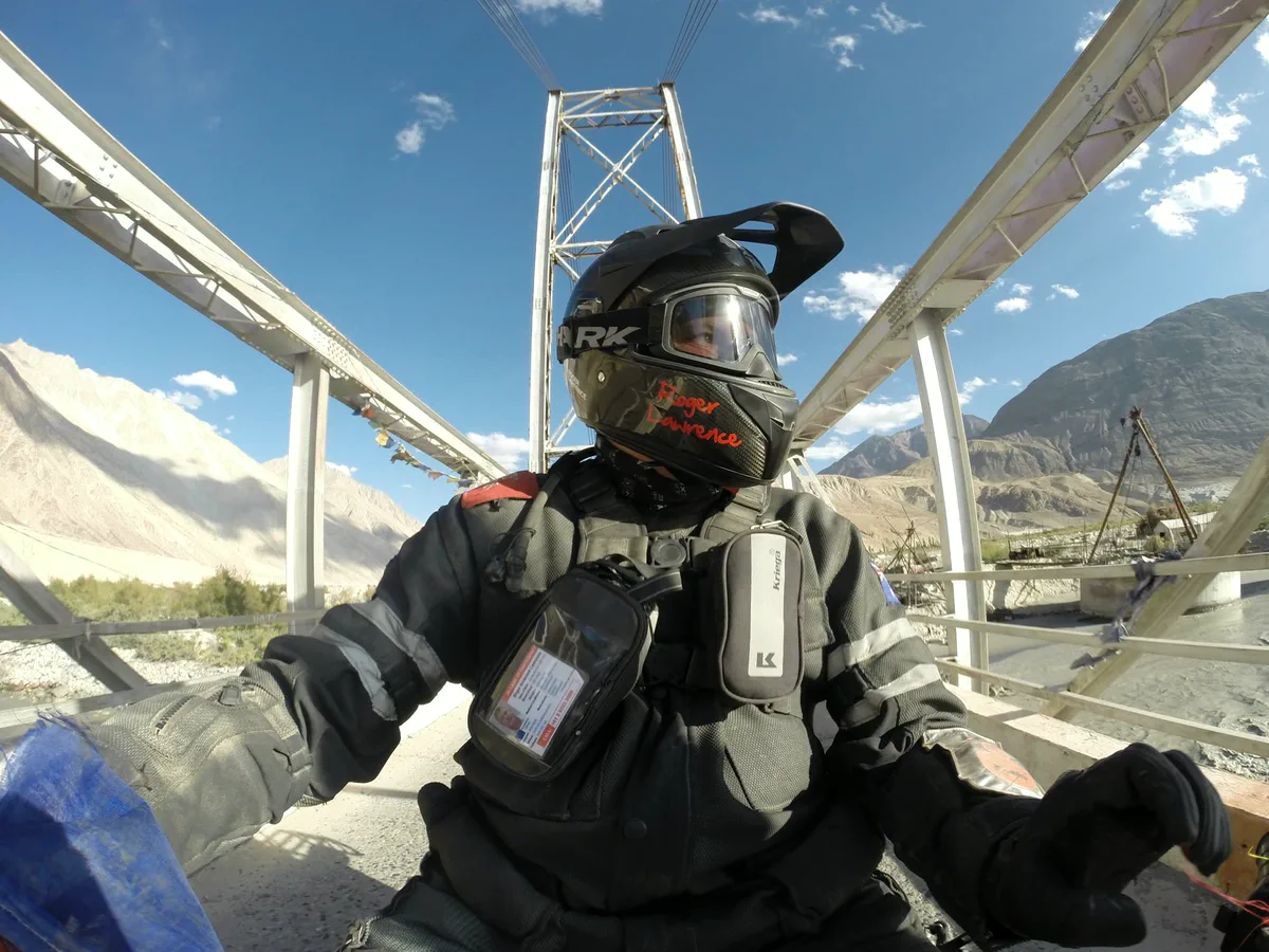 Roger Lawrence in motorcycle gear on a mountain bridge
