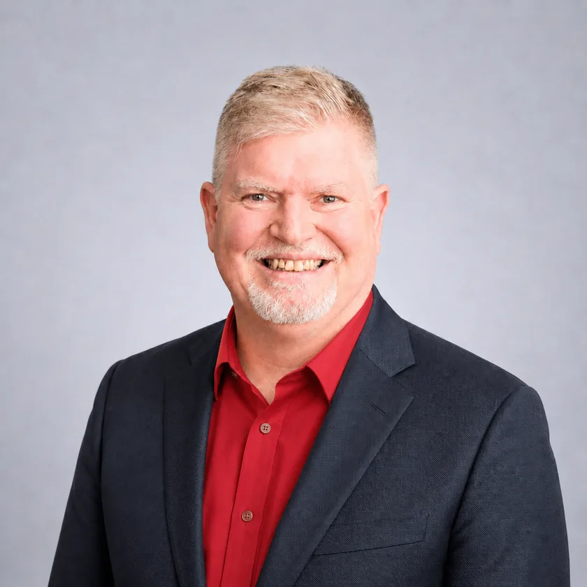 A formal portrait of Roger Lawrence in a dark blazer and red shirt